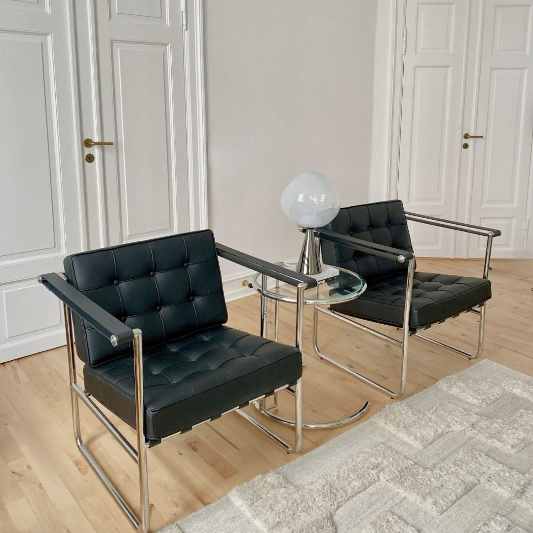 Lounge stol i sort læder med kromstel og faste armstøtter