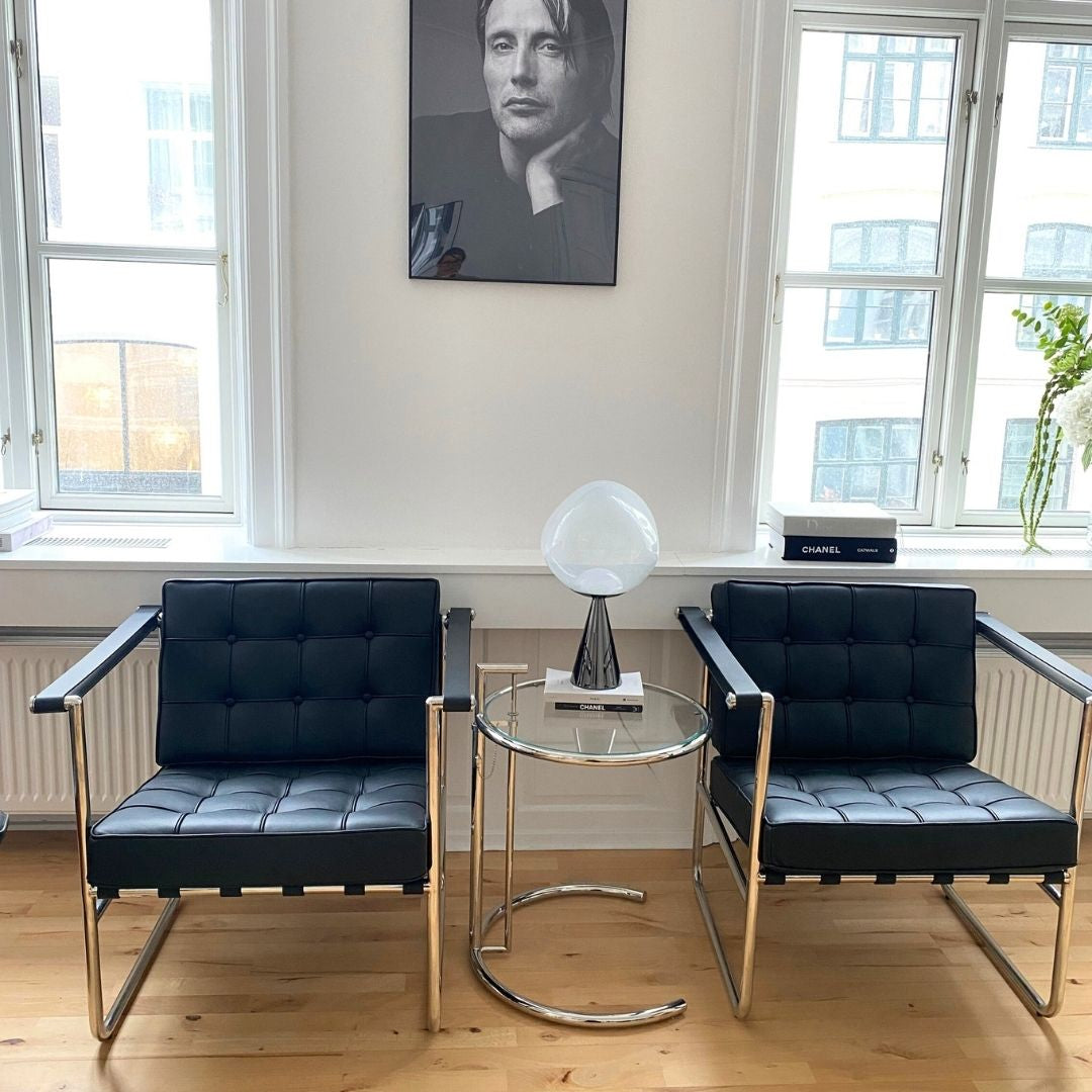 Moderne stol i sort læder med slankt stålstel og armlæn