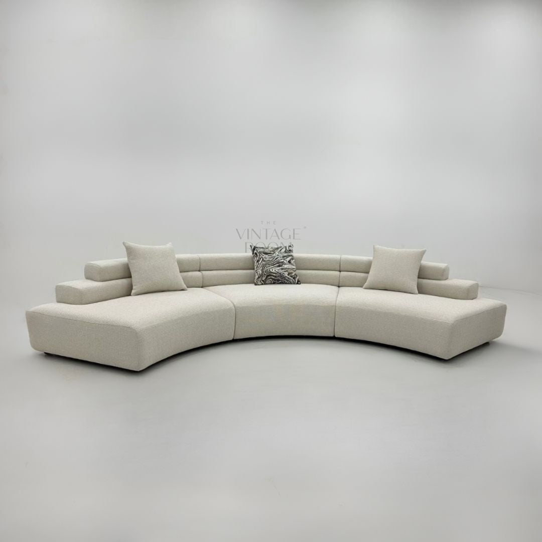 Skulpturel designsofa med rene linjer i creme stof til moderne hjem